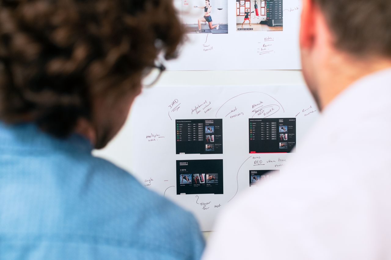about-01 Two business professionals brainstorming and planning software development with a whiteboard in an office.